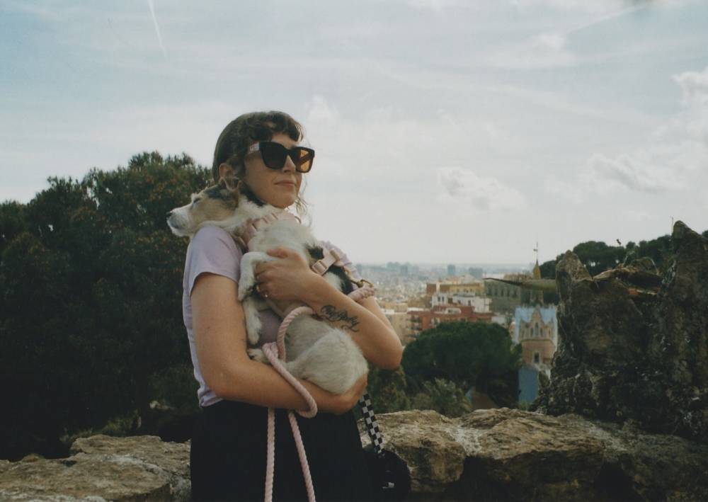 a girl wearing sunglasses hugs her small dog to her