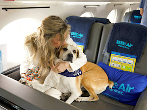 Woman and her dog on BARK Air airplane.