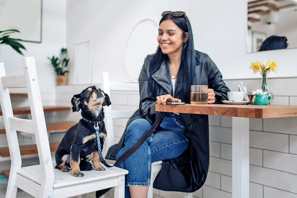 a pet parent sits with her dog in a cafe 