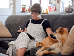 A woman sitting on a couch with a dog. 