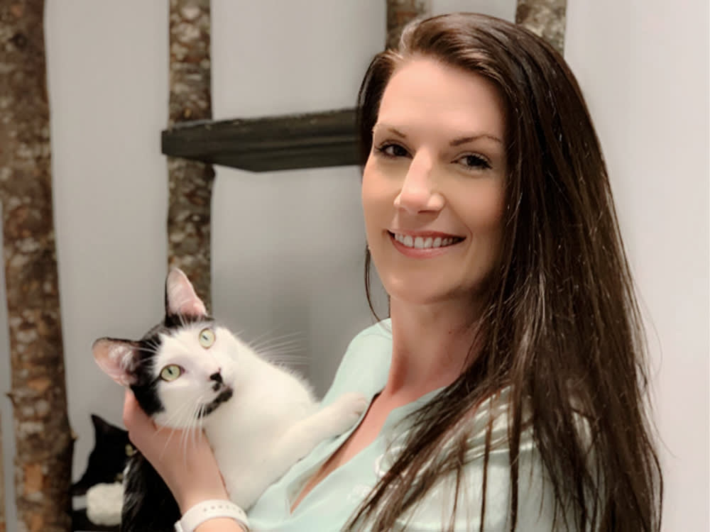 Cristin Tamburo smiling with a black-and-white cat. 