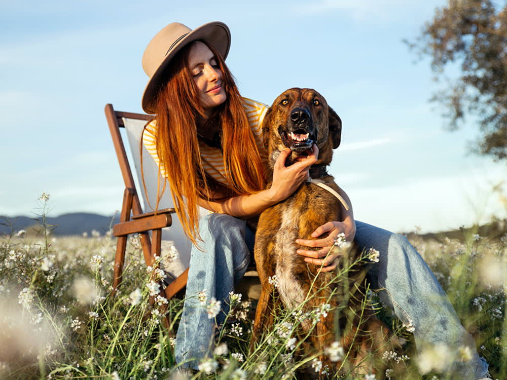 Woman sitting outside with her dog in a field.