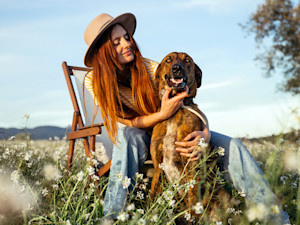 Woman sitting outside with her dog in a field.