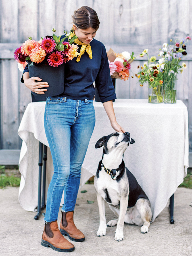 Woman holding Dahlia flowers while petting her dog.
