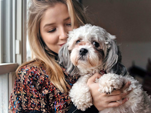 blonde woman holding older white dog
