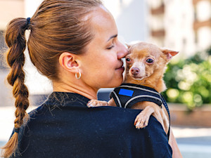 Woman snuggling her dog outside.