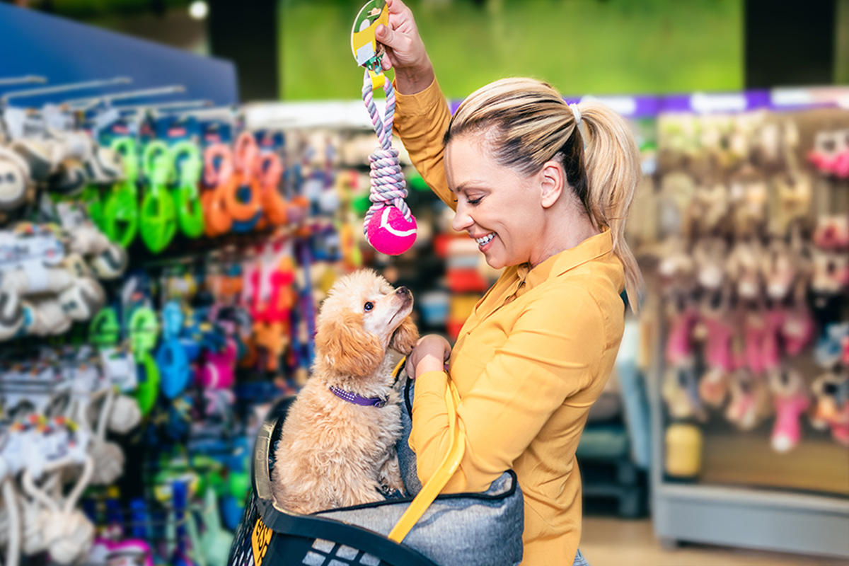 white blonde woman dangles a rope toe in front of her dog at the pet store