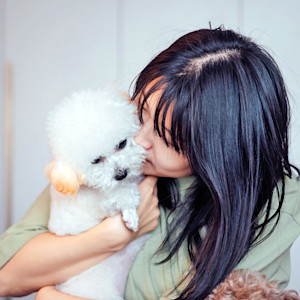 Woman smelling her small white dog.