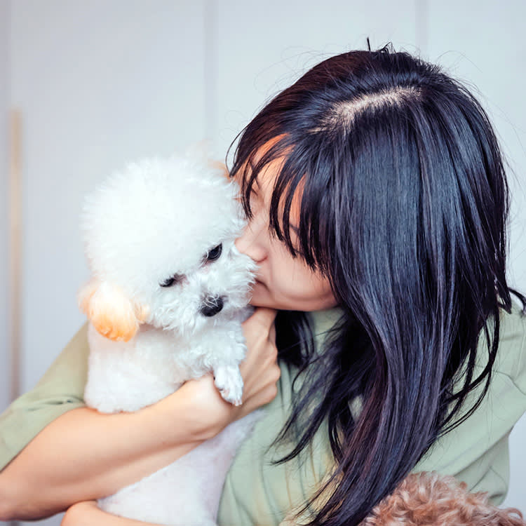 Woman smelling her small white dog.
