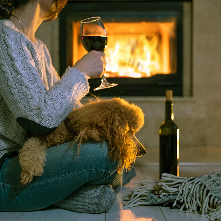 Woman drinking wine with her dog on her lap.