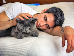 Man cuddling in bed with cat.