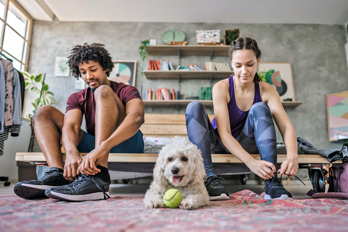 two people putting on their shoes next to a dog