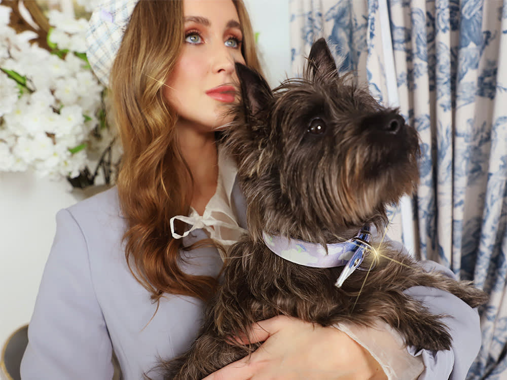 A glamour shot of a woman holding a dog while wearing matching colors.

