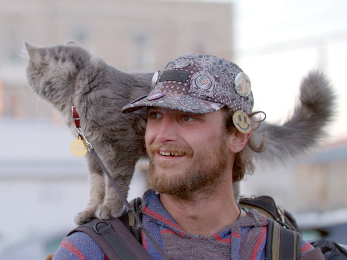 a man with a gray cat on his shoulders