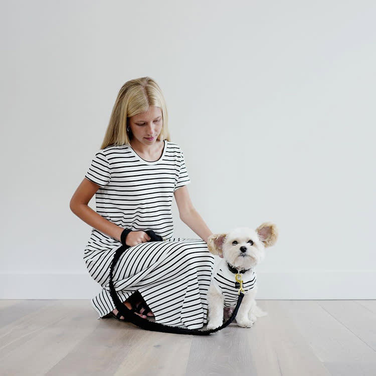 A woman and a dog wearing a matching outfit with stripes. 