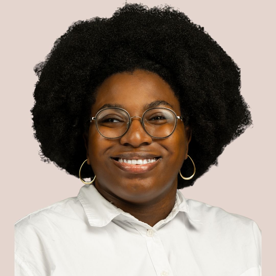 Headshot of a young Black woman with glasses and gold hoop earrings.}}