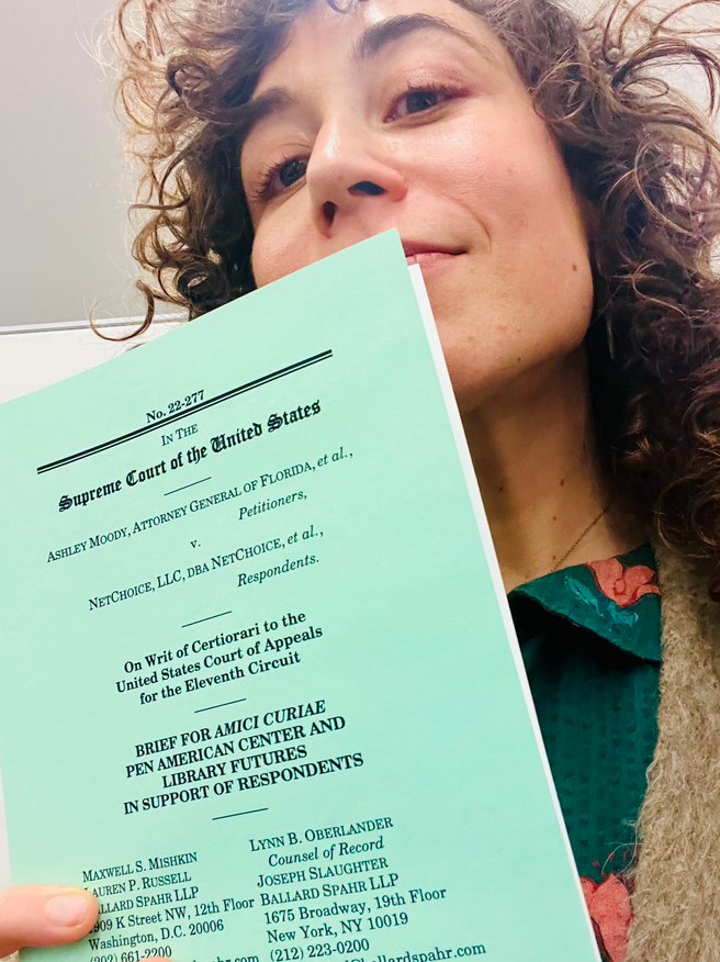 Jennie posing with a paper copy of the Supreme Court Brief