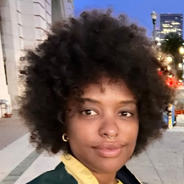 woman wiht an afro with city lights in the background}}