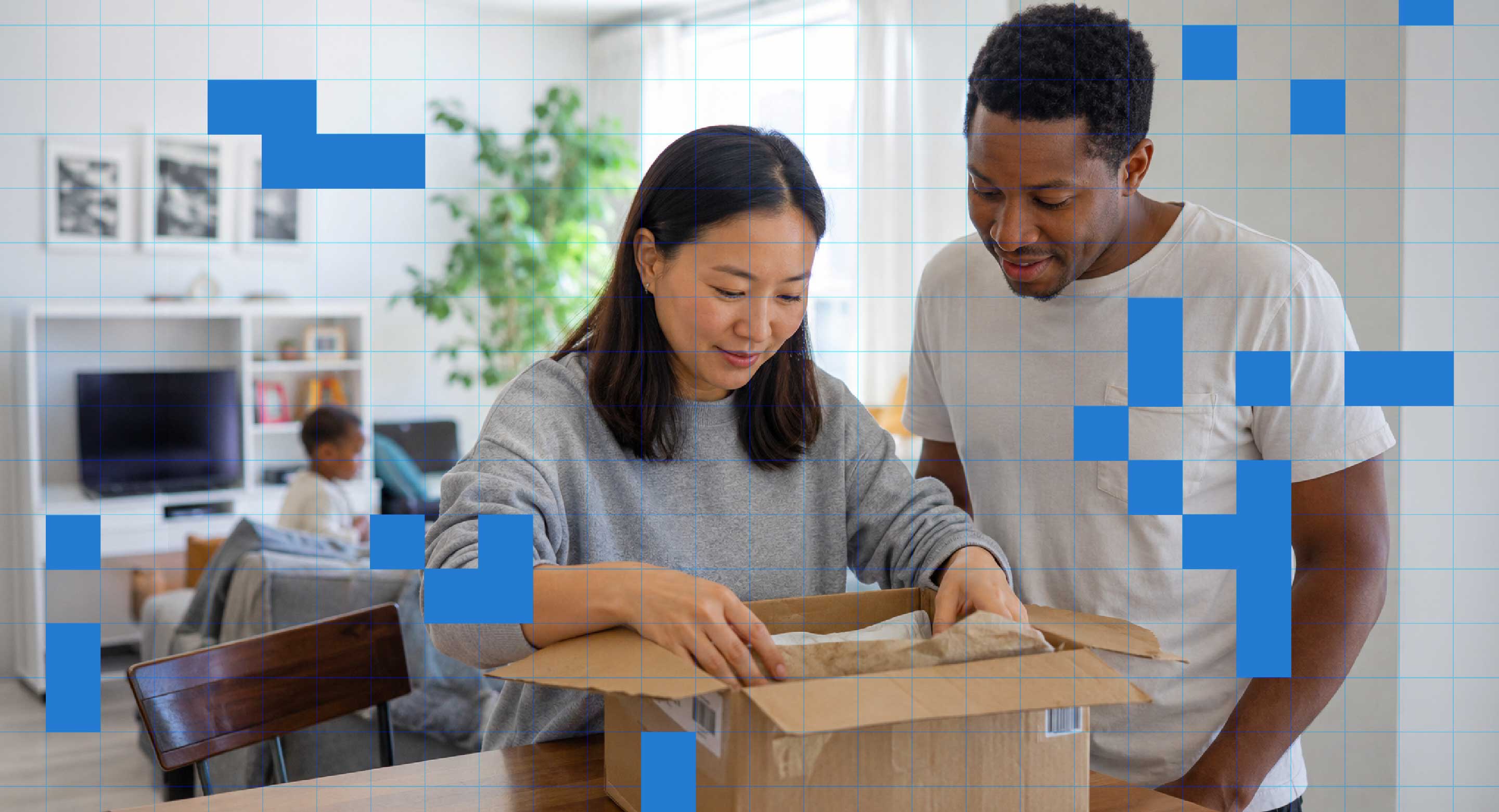 A couple open a box in their living room.