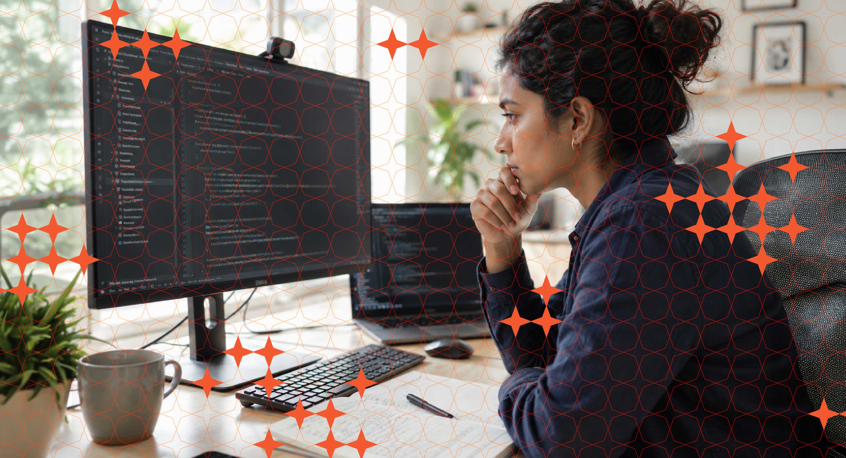 A woman sits in front of a desktop computer screen with lines of code displayed on it.