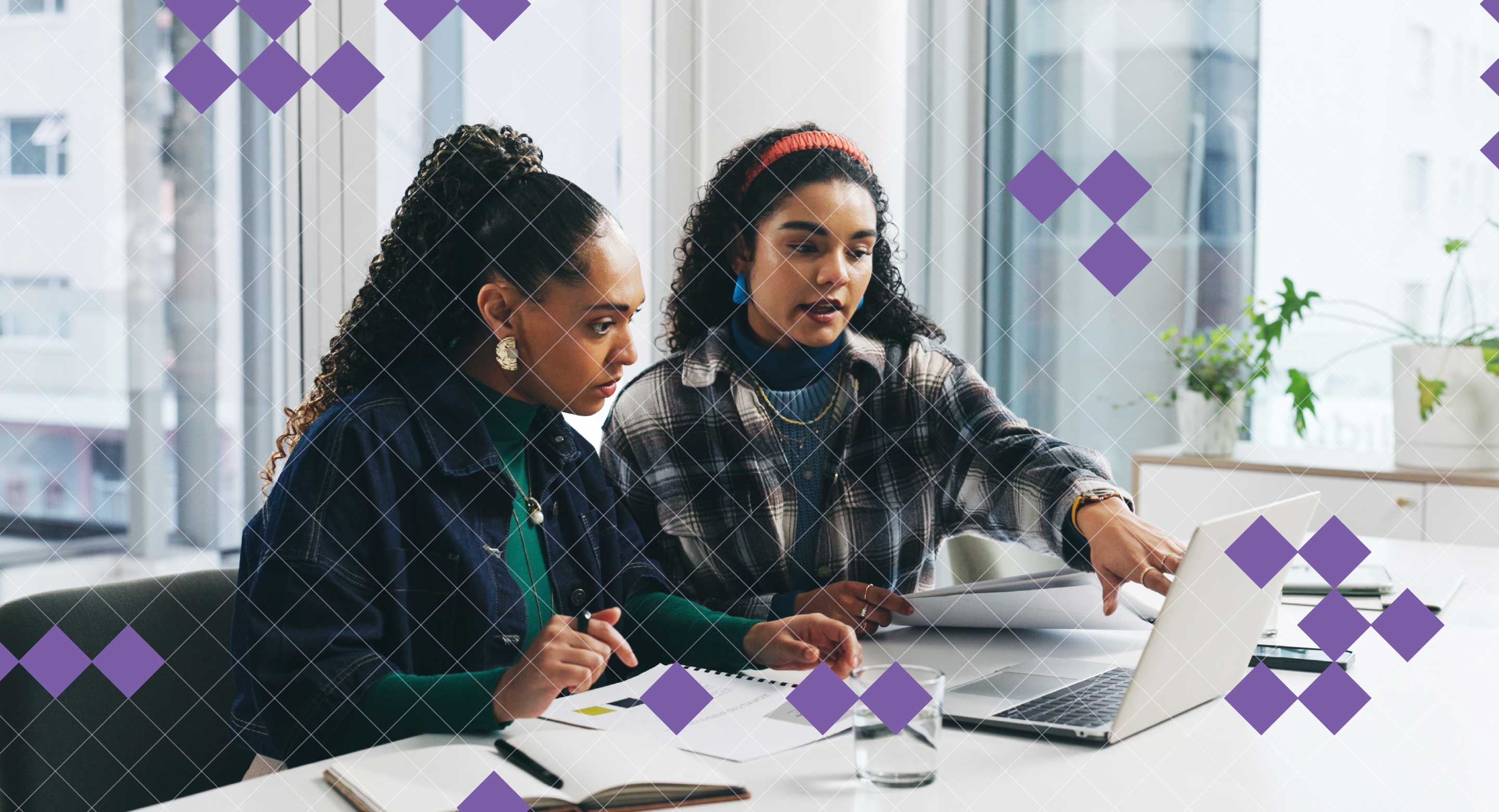 Two colleagues discuss work at a laptop