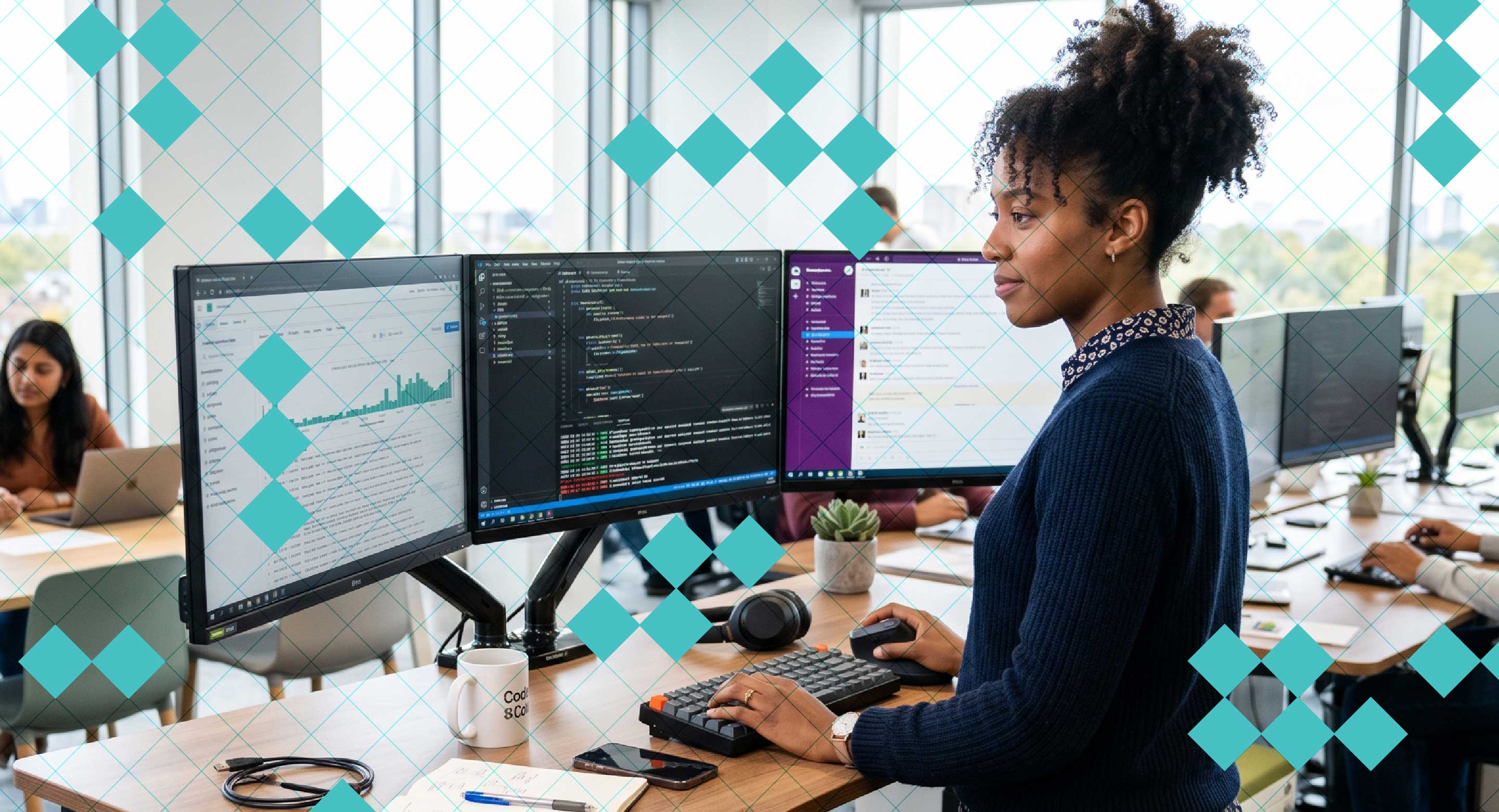 A woman stands in front of three monitors working at her desk.