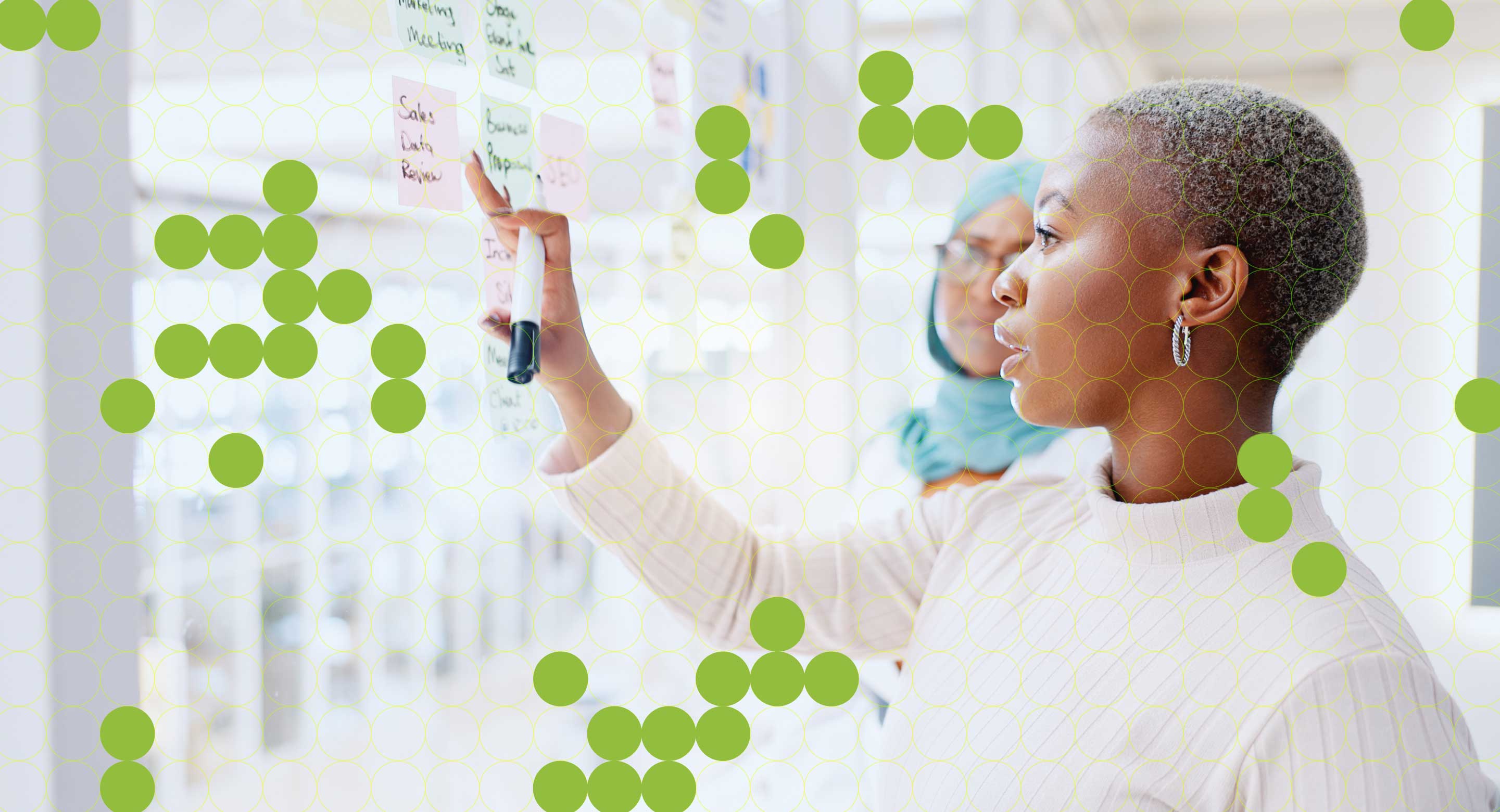 Two women work at a whiteboard.