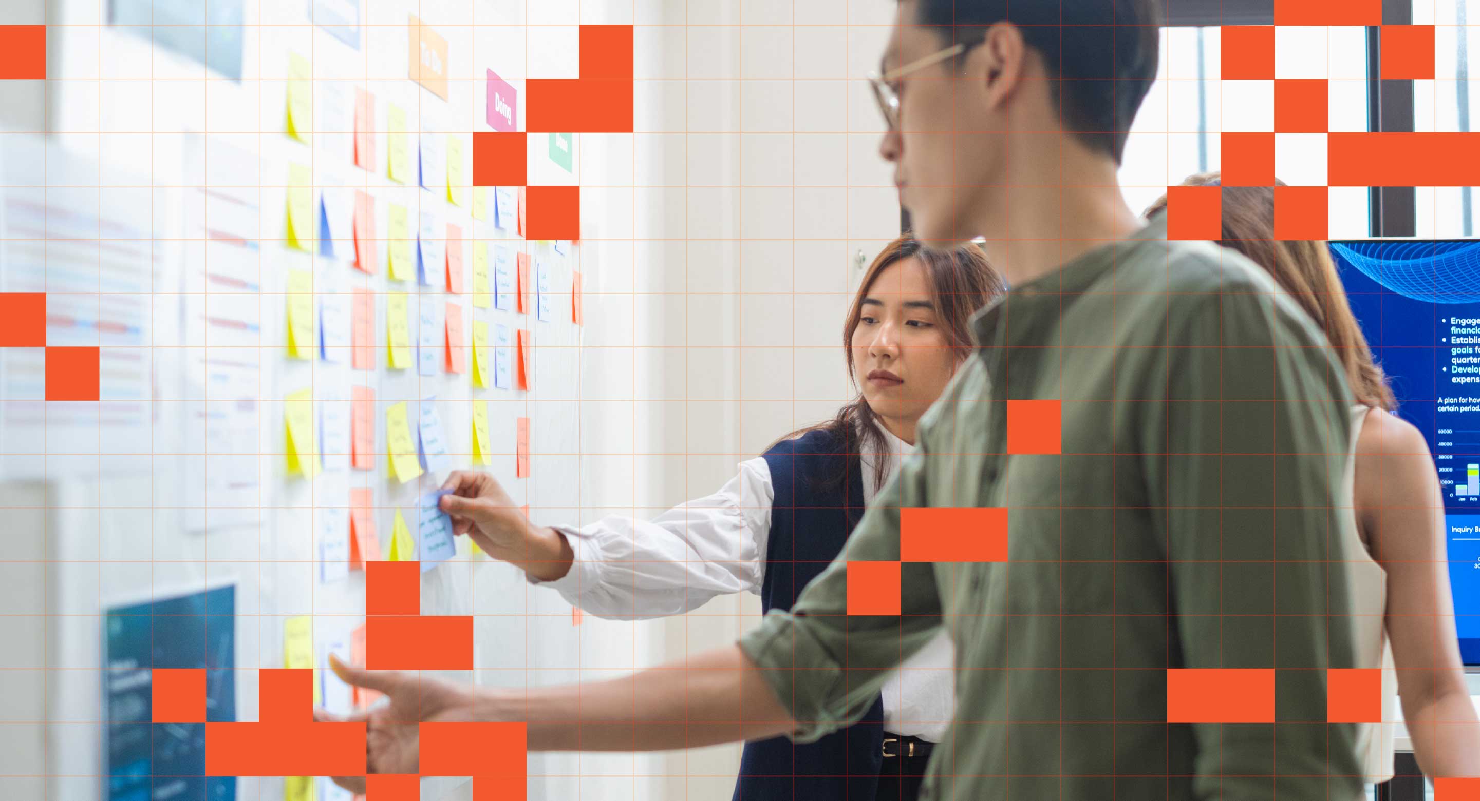 Team members review sticky notes posted on a wall.