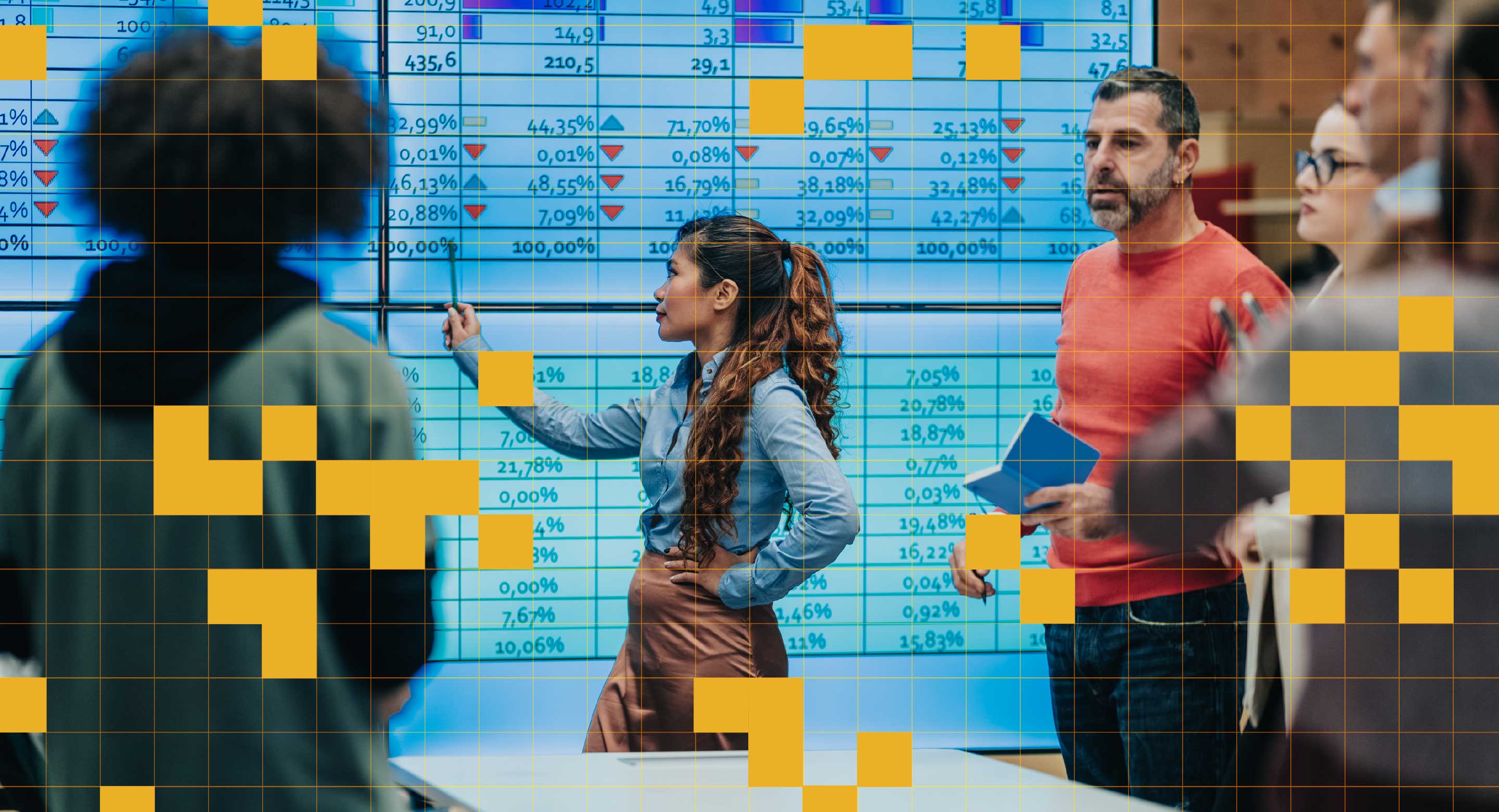 A team of people stand around looking at numbers displayed on a digital screen.
