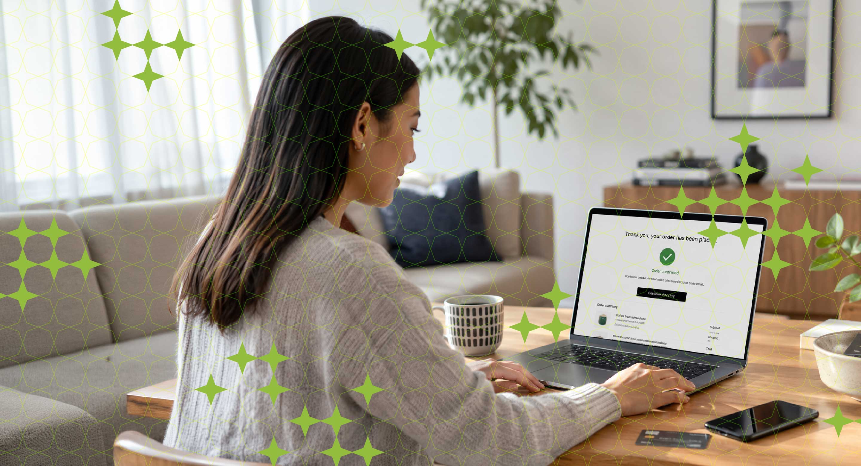 A woman sits in front of a laptop with a purchase confirmation screen visible on it.