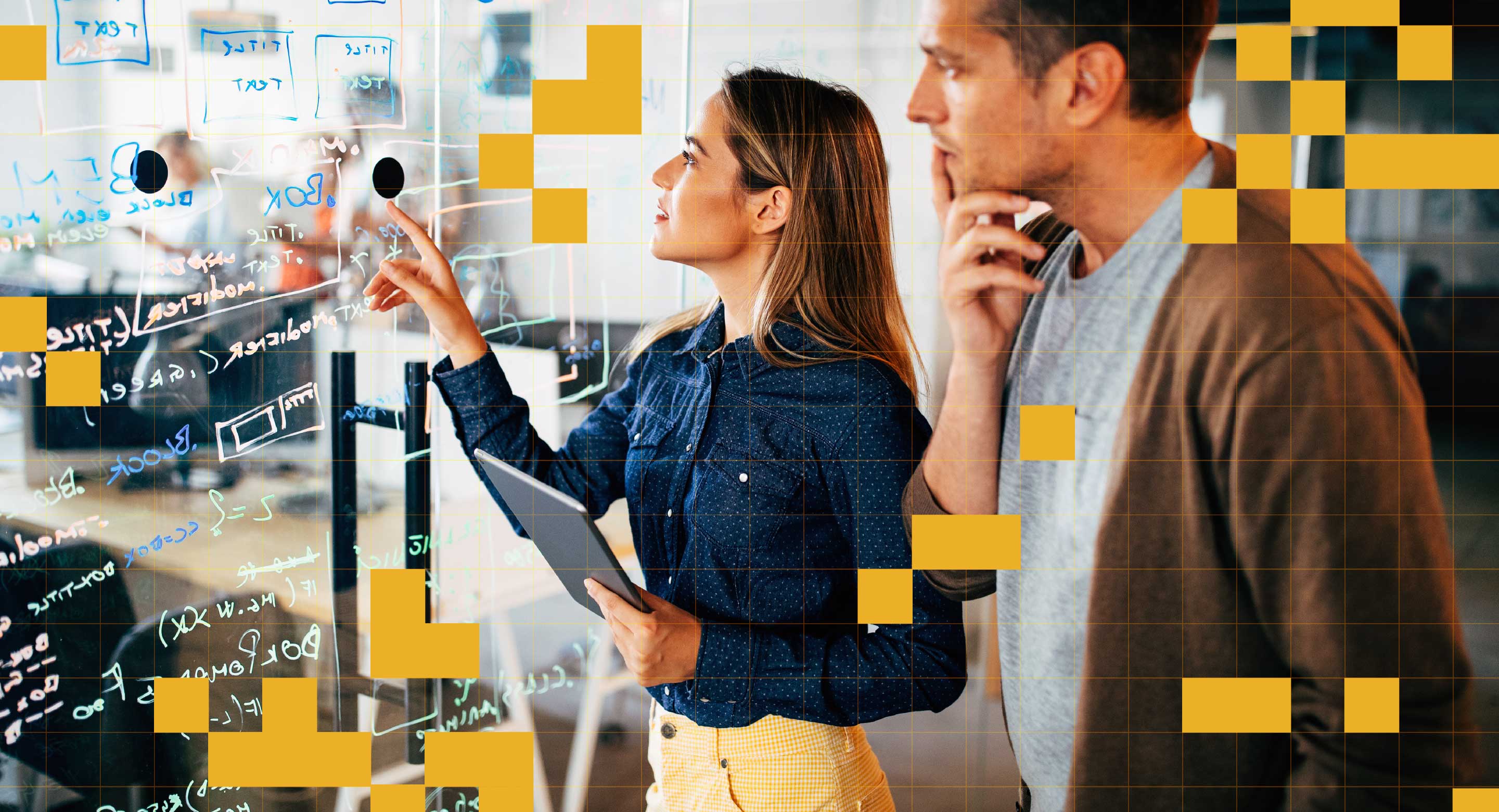 Two colleagues stand in front of an erasable glass wall with markings on it, contemplating a decision.