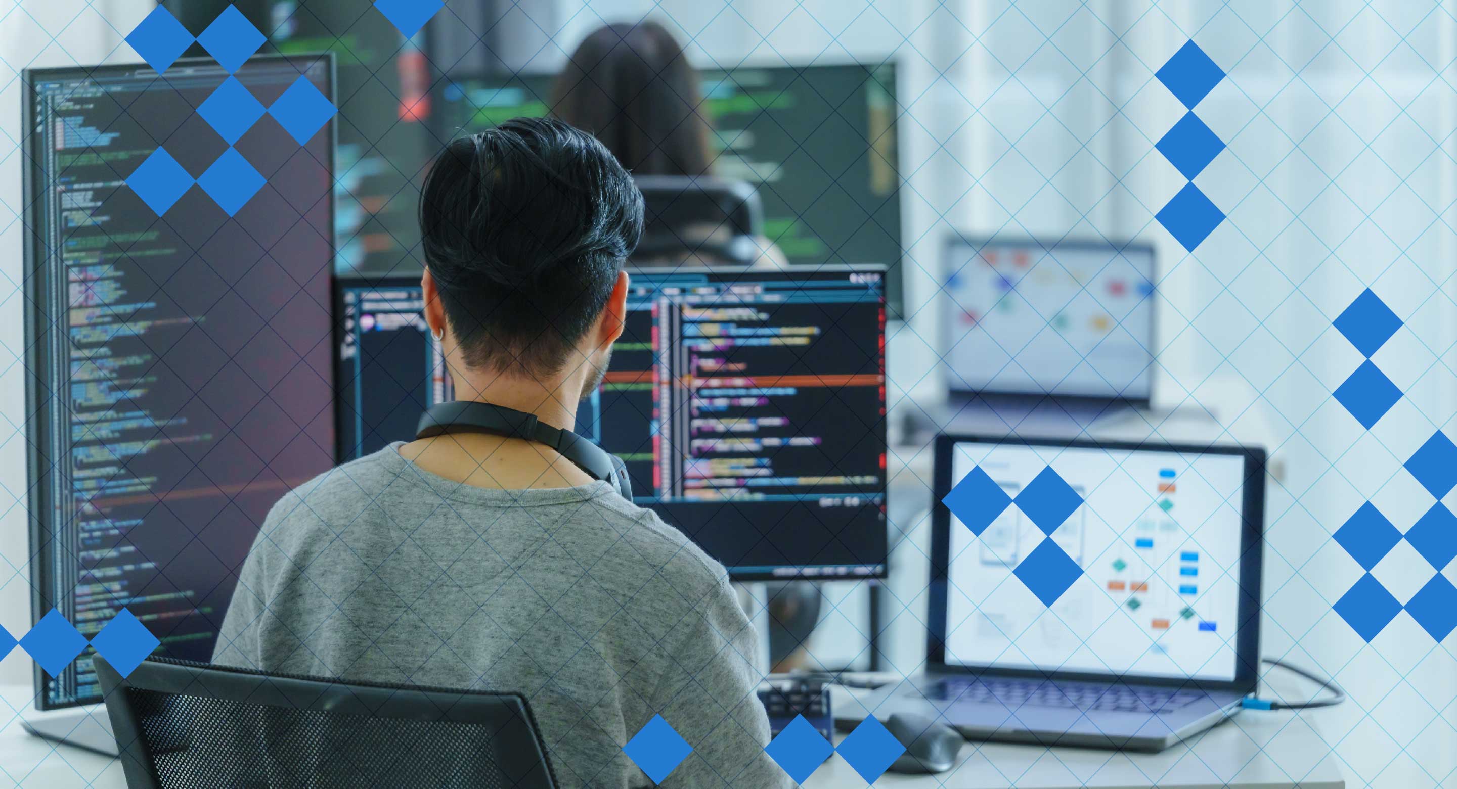 A developer sits in front of a computer set up with code on the screens