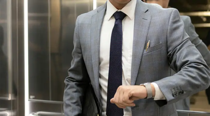 Man in suit checking his watch while waiting in an elevator