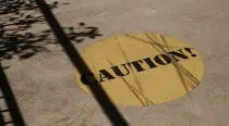 Round yellow "CAUTION!" sign painted on concrete