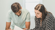 Man and woman standing together looking over some papers