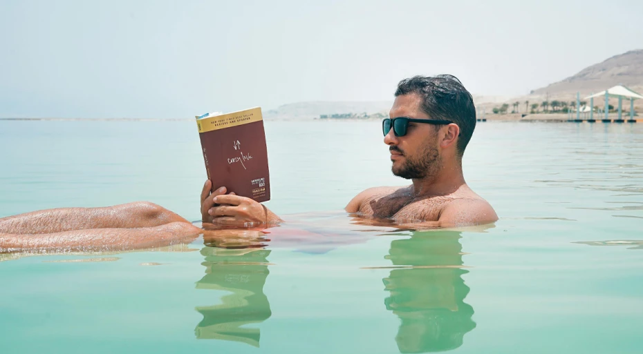 Man floating in the ocean or a lake reading a book