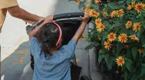 Young girl pushing a stroller up the hill, with flowers by her side