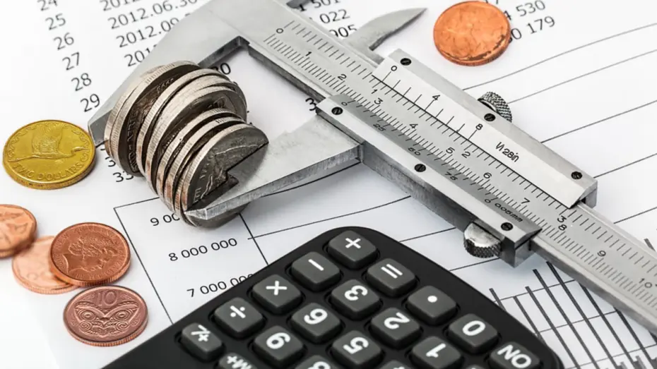 Coins and calculator sitting on sheet with numbers