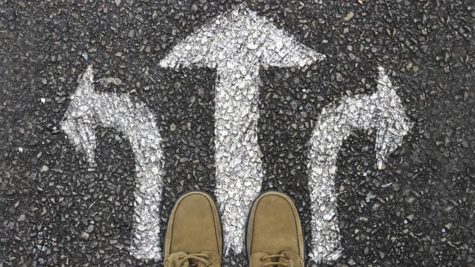 Top view of shoes on concrete, painted arrows symbolising decisions