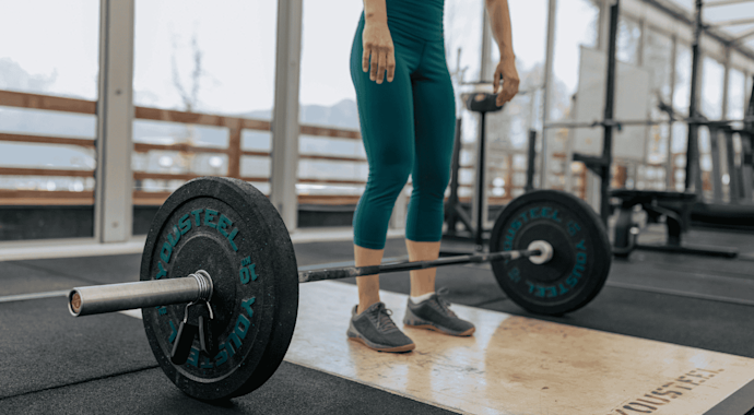 Woman lifting barbell weights in a gym.