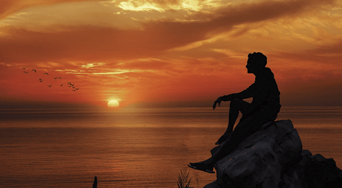 Man silhoutted against a sunset over the ocean