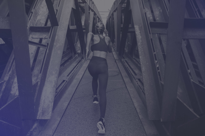 A woman is sprinting across a steel bridge.