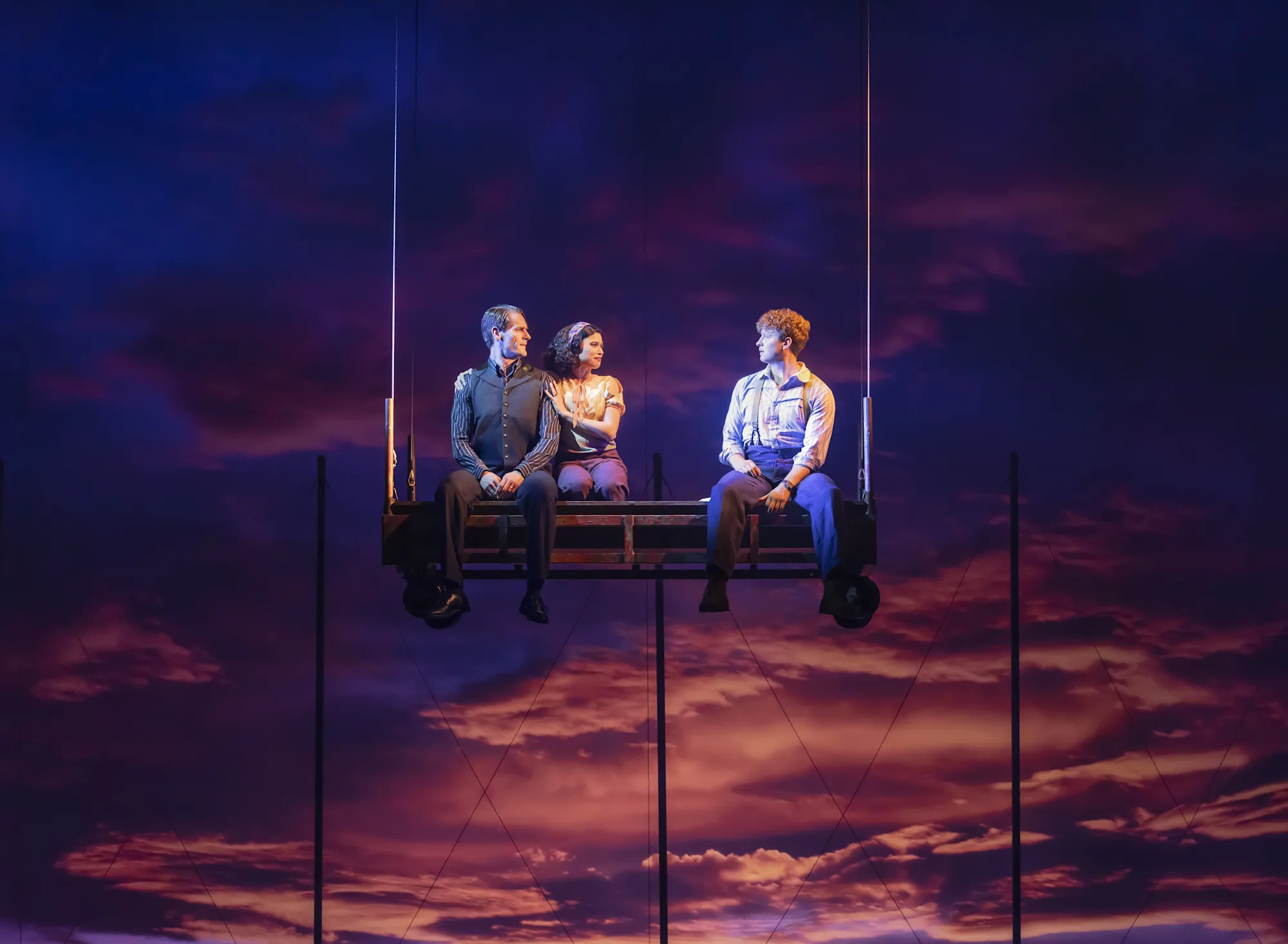 Connor Sullivan, Helen Krushinski, and Zachary Keller sit on a large swing suspended high in the air. Photo by Matthew Murphy for MurphyMade