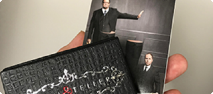 Person holding a picture of Penn and Teller