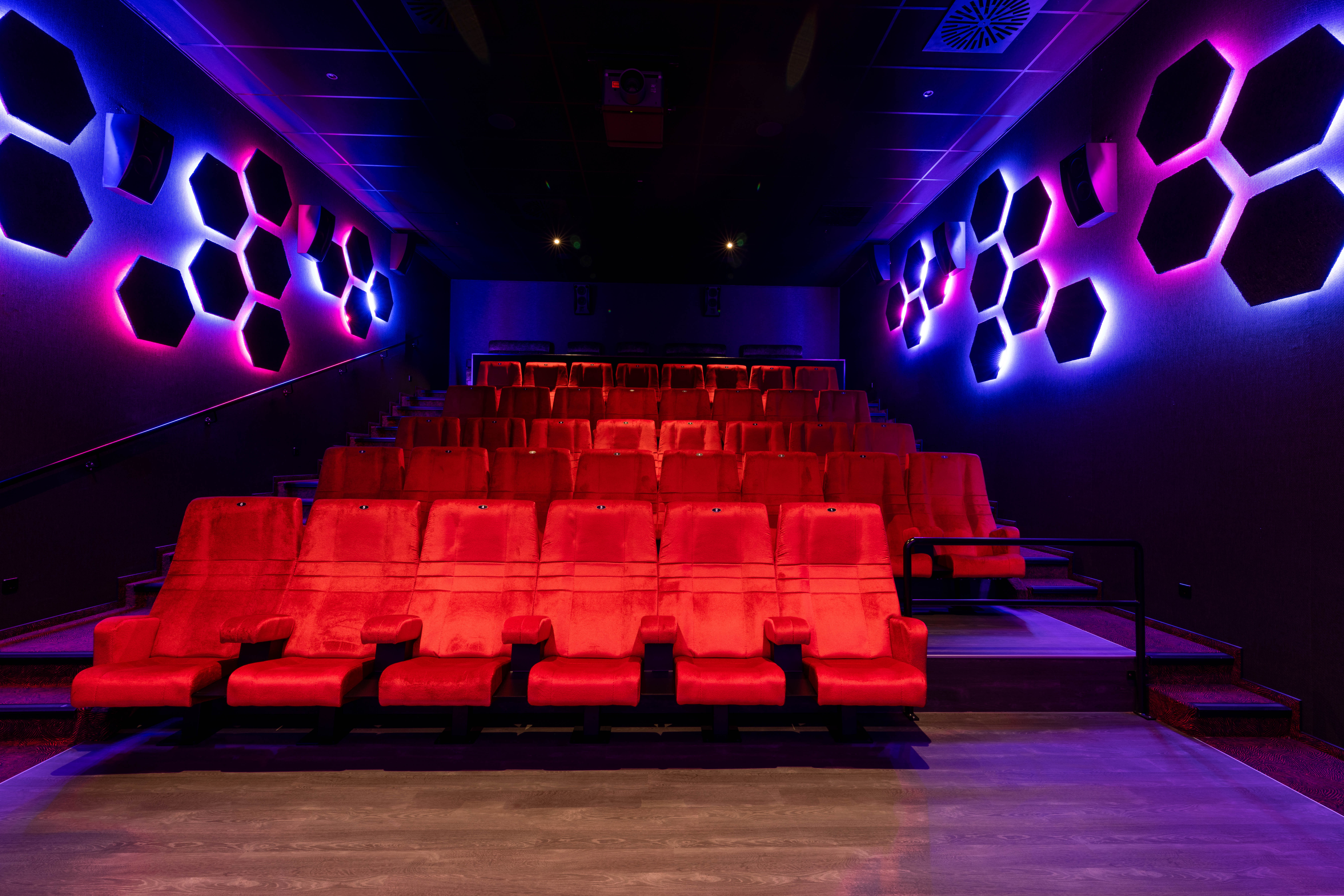 Foto, das einen dunklen Kinosaal mit roten Kinostühlen des Cineplex Erding zeigt. 