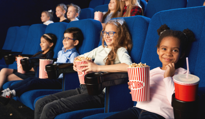 Hier sieht man glückliche Kinder im Kino sitzen