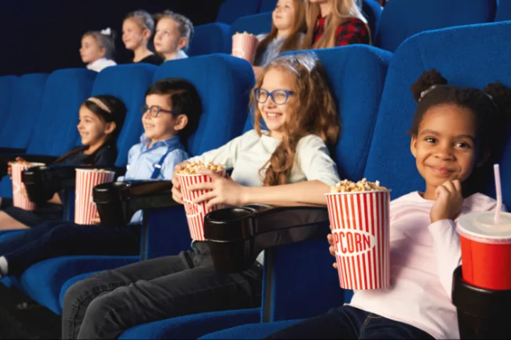 Hier sieht man glückliche Kinder im Kino sitzen