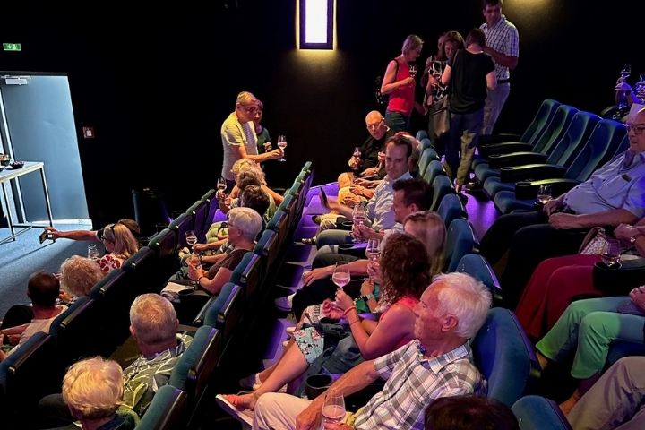  „Gäste sitzen im Kinosaal auf den Plätzen und trinken Wein vor Beginn des Films“