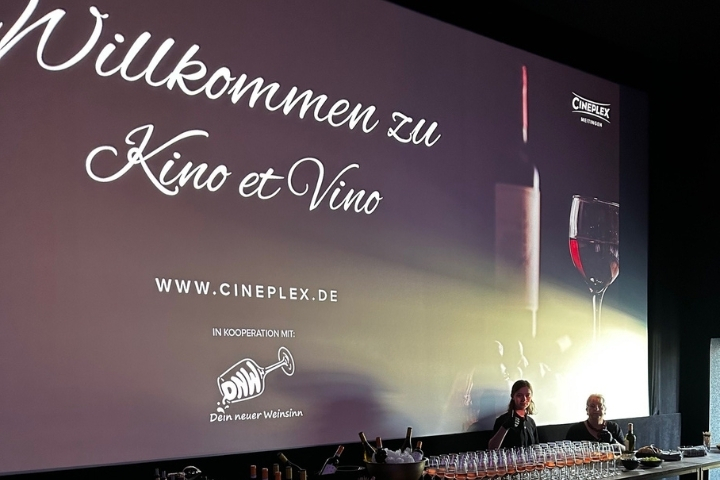 „Große Kinoleinwand mit Willkommensgruß zu Kino et Vino und Weinausschank davor“