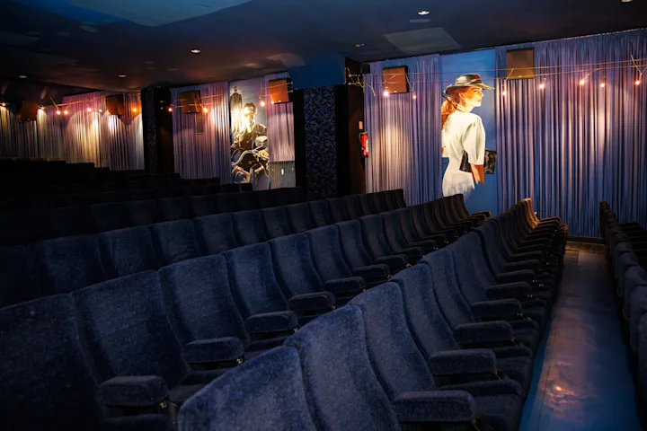 Kinosaal mit blauen Sesseln und Filmstars an der Wand